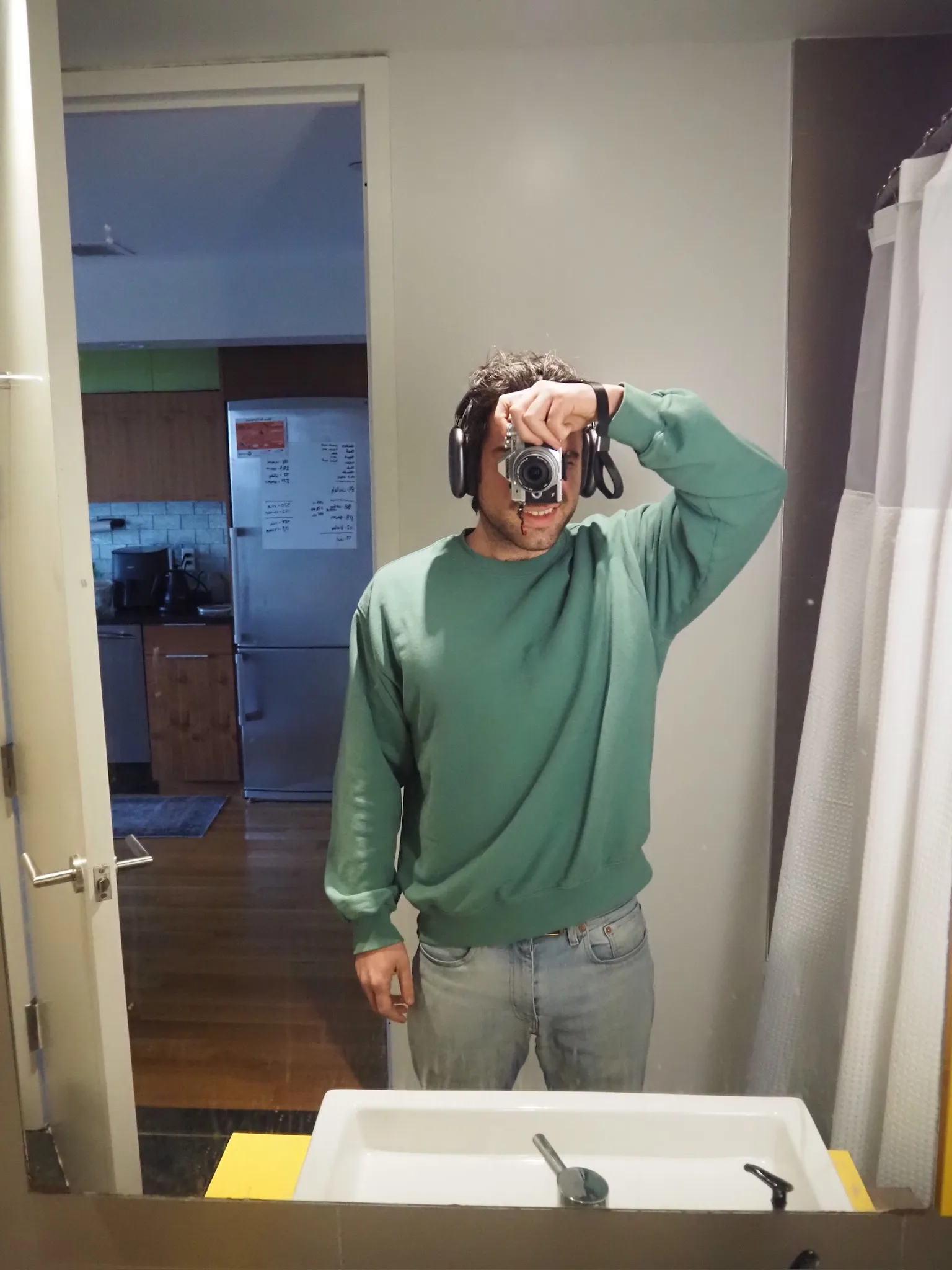 An image of a man holding a camera in a bathroom